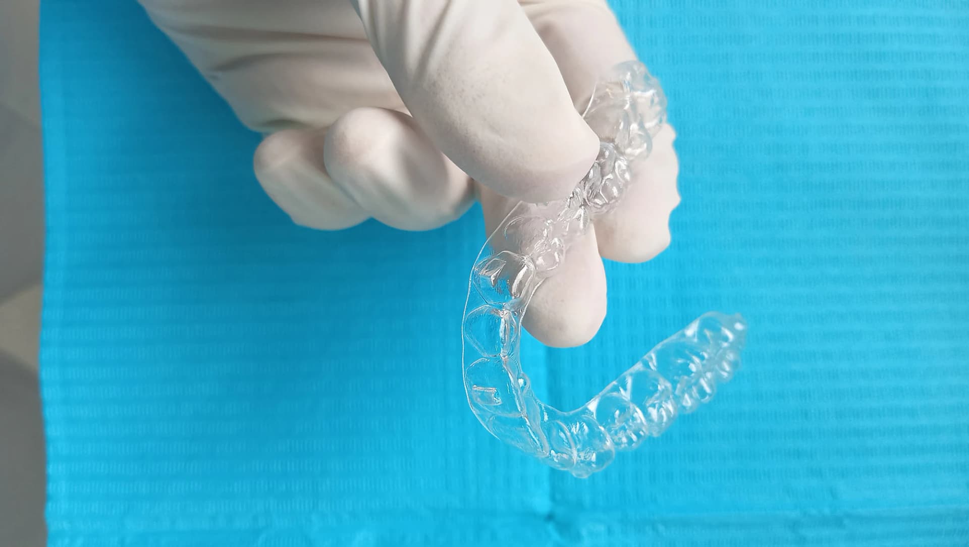 Allineatore trasparente tenuto con guanti clinici su un telo blu